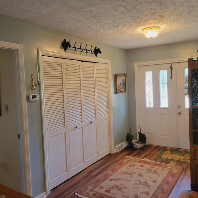 entrance foyer featuring visible vents, a textured ceiling, and wood finished floors