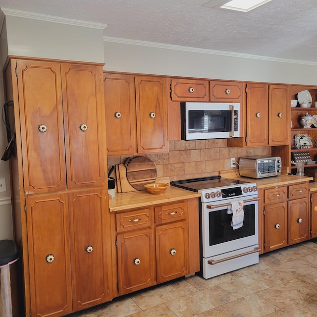 kitchen featuring stainless steel microwave, backsplash, crown molding, light countertops, and electric stove