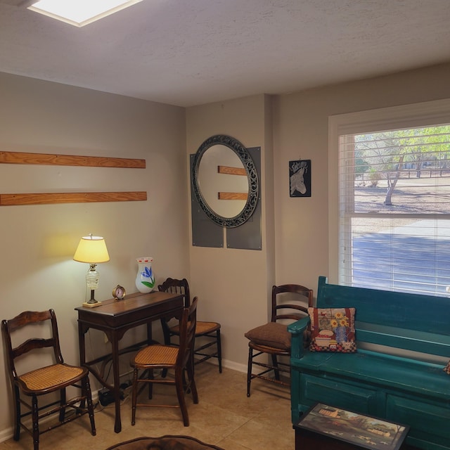 living area featuring light tile patterned floors, a textured ceiling, and baseboards