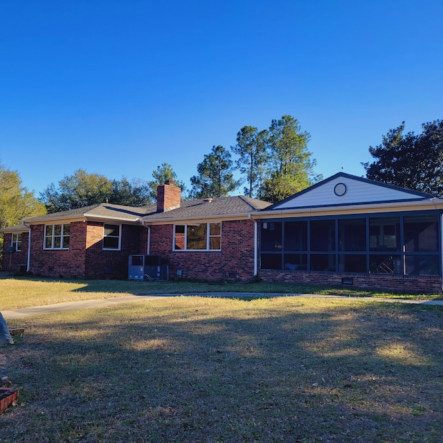 rear view of house with crawl space, a lawn, a sunroom, and a chimney