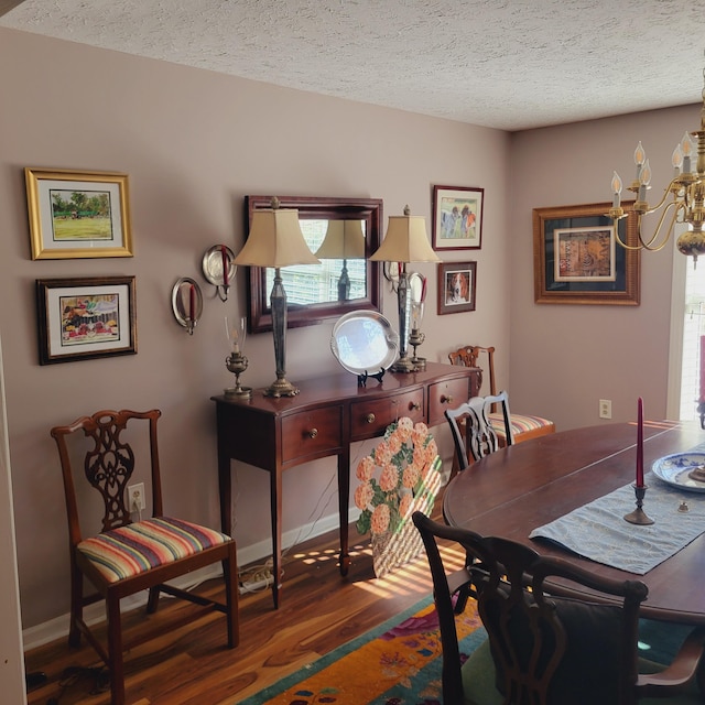 dining room featuring a chandelier, a textured ceiling, baseboards, and wood finished floors