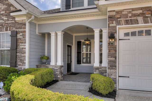 view of exterior entry featuring stone siding, covered porch, and a shingled roof