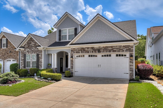 craftsman inspired home featuring stone siding, driveway, a garage, a front yard, and roof with shingles