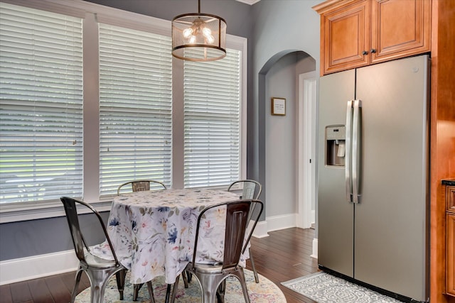 dining room featuring baseboards, hardwood / wood-style floors, and arched walkways