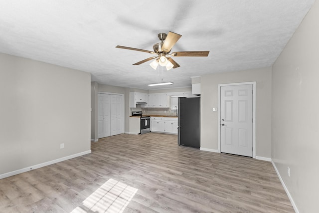 unfurnished living room with a textured ceiling, light hardwood / wood-style flooring, ceiling fan, and sink