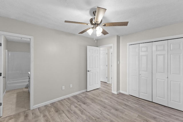 unfurnished bedroom with a textured ceiling, ceiling fan, light hardwood / wood-style flooring, connected bathroom, and a closet