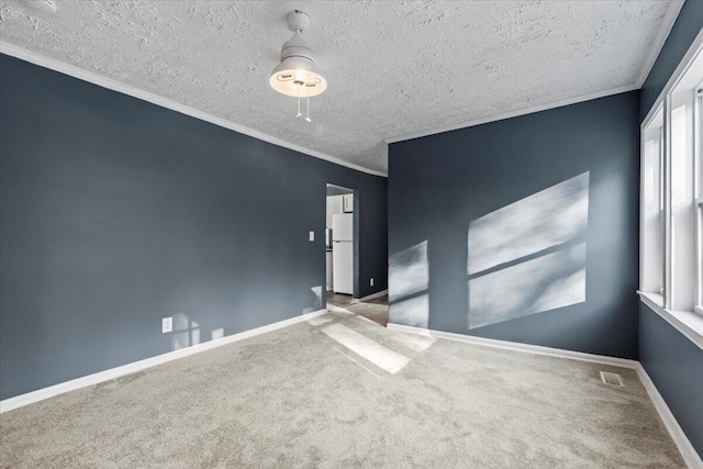 empty room with carpet, a textured ceiling, and crown molding