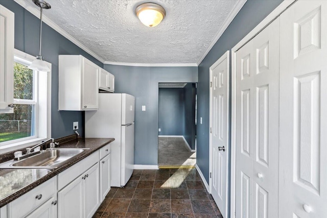 kitchen with ornamental molding, sink, white refrigerator, white cabinetry, and hanging light fixtures