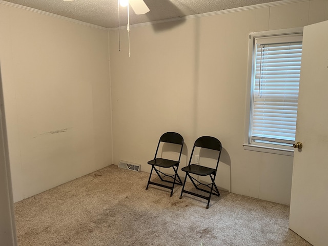 sitting room with light carpet, a textured ceiling, and ornamental molding