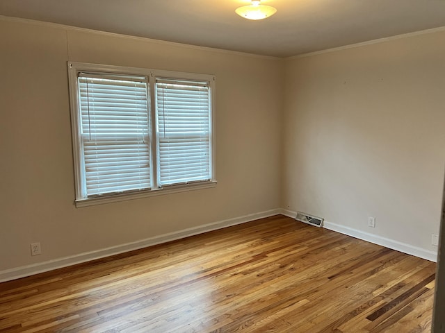 spare room featuring ornamental molding and light hardwood / wood-style flooring