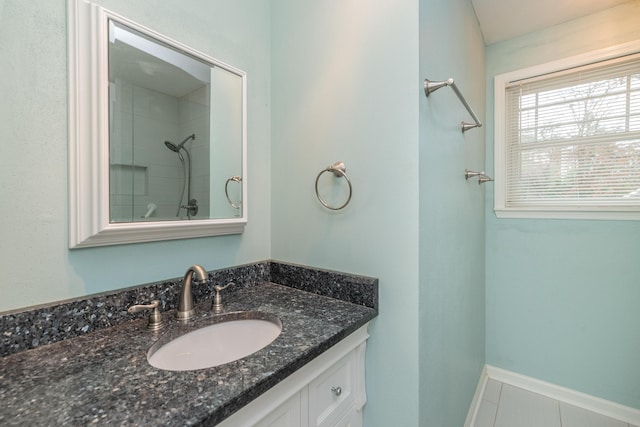 bathroom with tile patterned flooring, vanity, and a tile shower