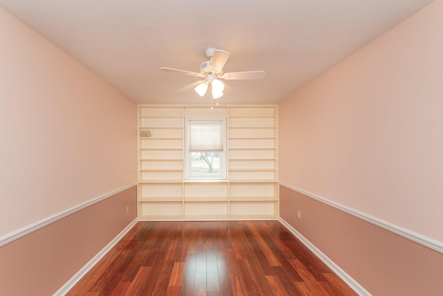 spare room featuring built in shelves, ceiling fan, and dark hardwood / wood-style flooring