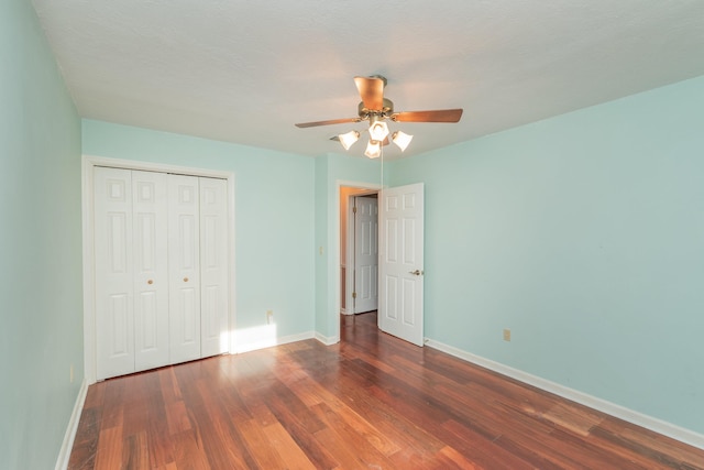 unfurnished bedroom featuring ceiling fan, dark wood-type flooring, and a closet