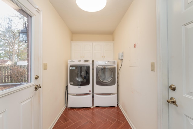 clothes washing area with cabinets, washing machine and clothes dryer, electric panel, and dark parquet flooring