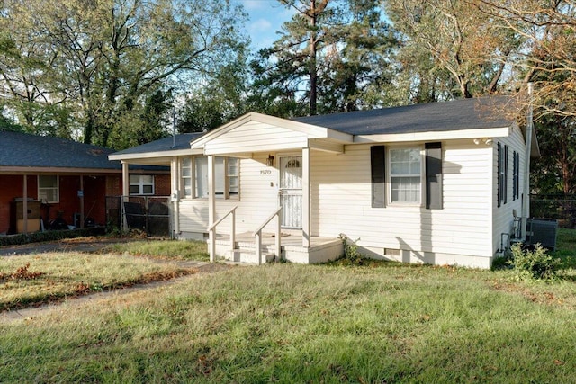 view of front of house with central AC and a front yard