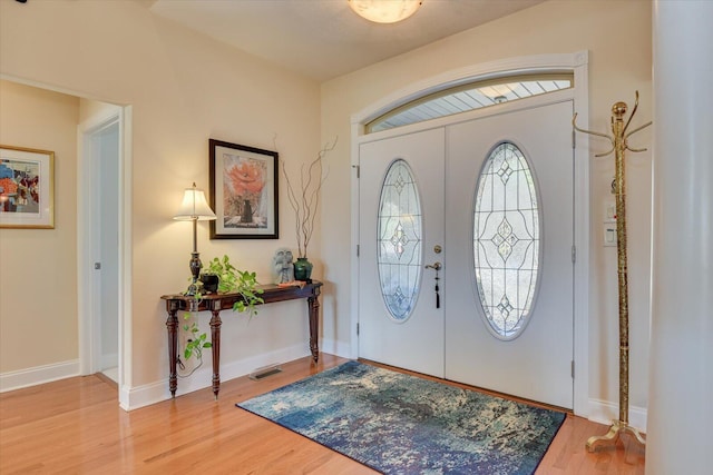 foyer featuring wood finished floors, visible vents, and baseboards