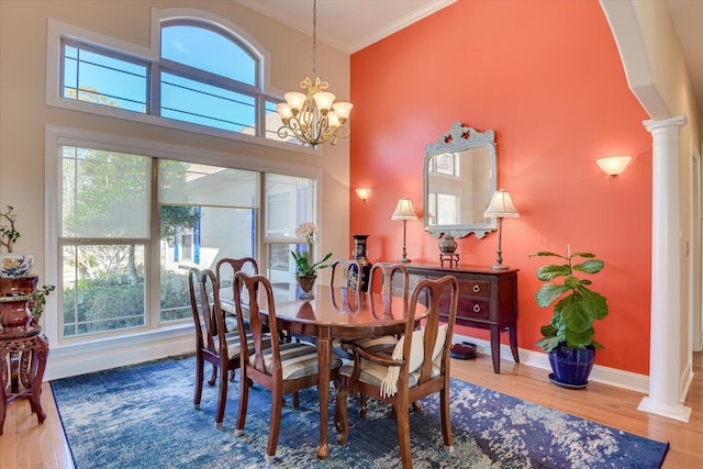 dining room featuring wood finished floors, decorative columns, and a notable chandelier