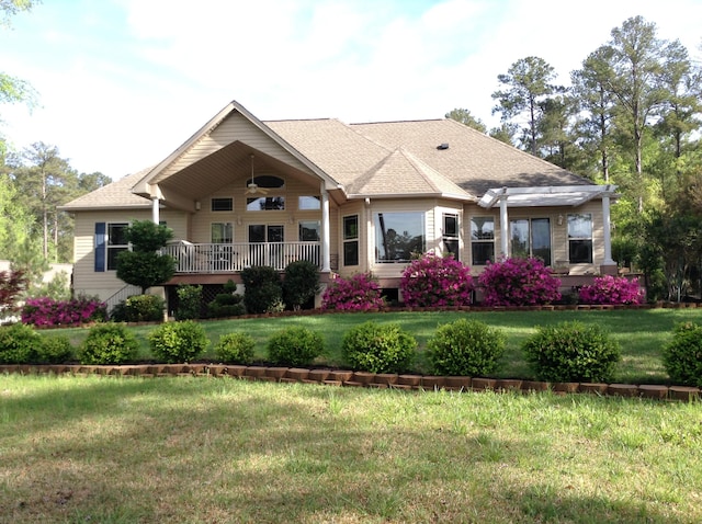 exterior space featuring roof with shingles, a ceiling fan, and a yard