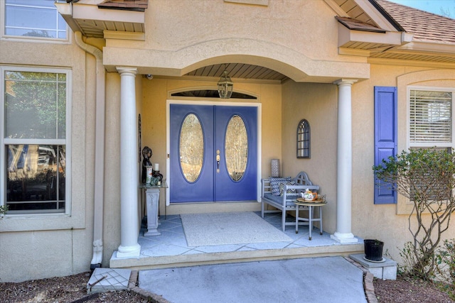 doorway to property featuring covered porch, french doors, roof with shingles, and stucco siding