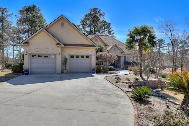 view of front of house featuring a garage, concrete driveway, and stucco siding