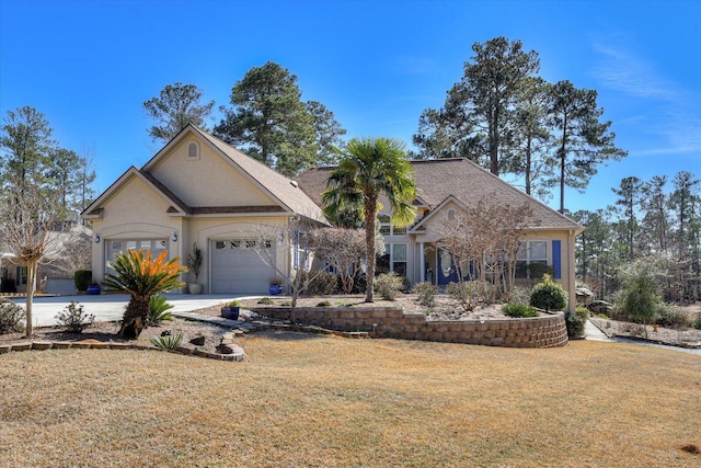 view of front of house featuring a garage, concrete driveway, a front lawn, and stucco siding