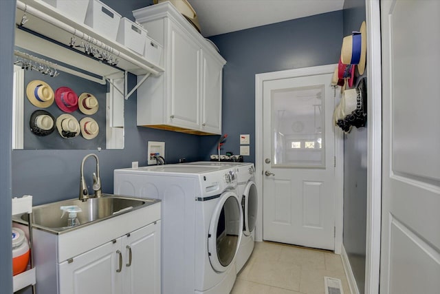 clothes washing area featuring light tile patterned floors, cabinet space, visible vents, a sink, and washer and dryer