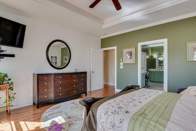 bedroom featuring ensuite bathroom, wood finished floors, baseboards, ornamental molding, and a raised ceiling