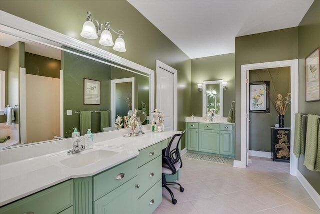 bathroom with tile patterned flooring, baseboards, two vanities, and a sink