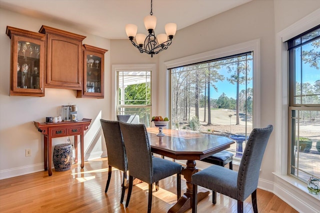 dining space with light wood-style flooring, baseboards, and an inviting chandelier