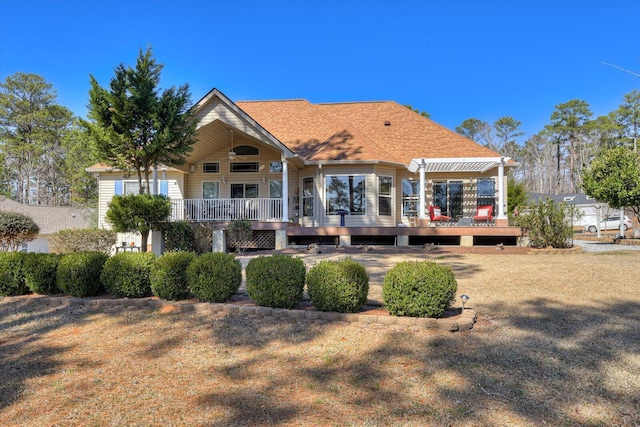 back of house featuring a shingled roof and a wooden deck