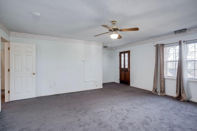 empty room with a ceiling fan, a wealth of natural light, baseboards, and dark colored carpet