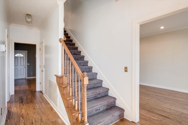 staircase featuring wood-type flooring and ornamental molding