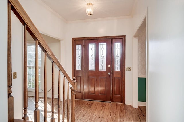 entryway featuring ornamental molding, light wood-type flooring, stairway, and baseboards