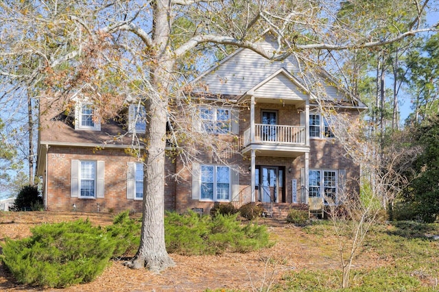 view of front of home with brick siding and a balcony