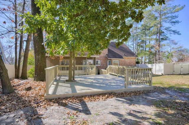 rear view of property featuring a deck, brick siding, and a fenced backyard