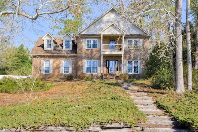 view of front facade featuring brick siding and a balcony