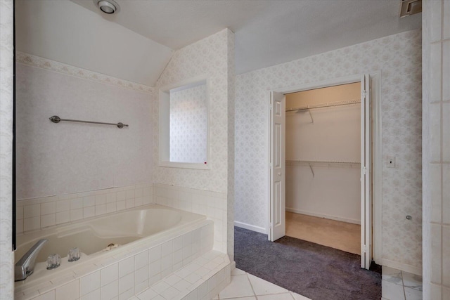 bathroom with lofted ceiling, a spacious closet, a bath, and wallpapered walls