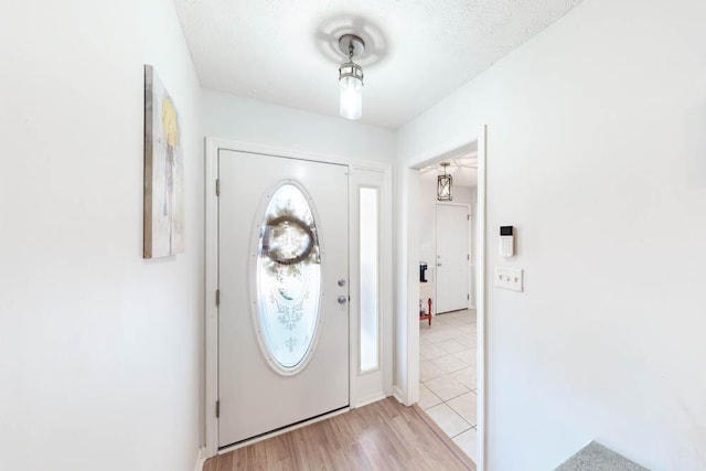 foyer entrance with plenty of natural light, light wood-type flooring, and a textured ceiling