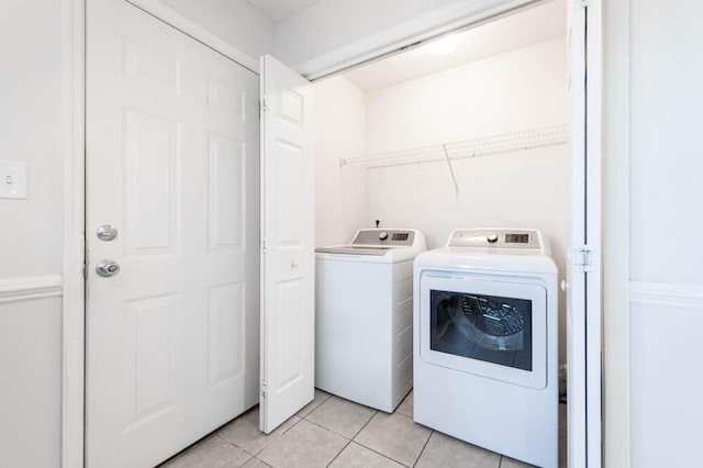 clothes washing area featuring washer and dryer and light tile patterned floors