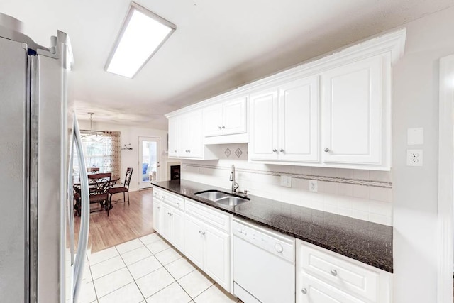 kitchen featuring stainless steel refrigerator, white cabinetry, sink, white dishwasher, and light tile patterned flooring