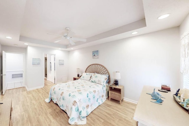 bedroom featuring light wood-type flooring, a raised ceiling, and ceiling fan