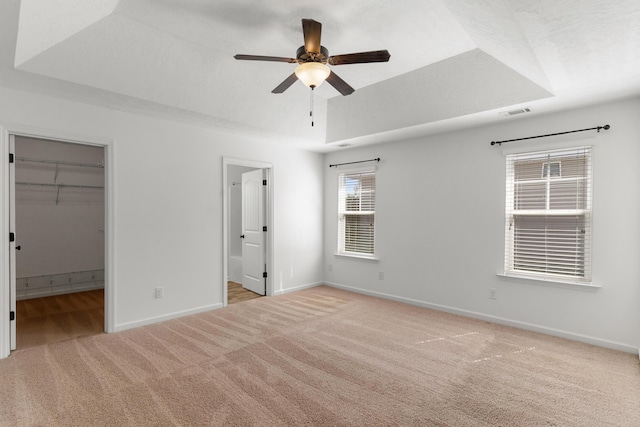 7058 Summerton Dr, Augusta, GA 30909 - unfurnished bedroom with visible vents, light colored carpet, baseboards, ensuite bathroom, and a tray ceiling
