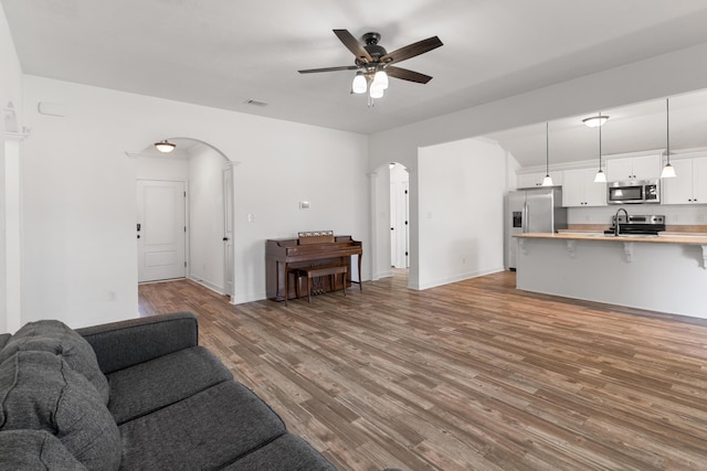 7058 Summerton Dr, Augusta, GA 30909 - living room featuring ceiling fan, arched walkways, baseboards, wood finished floors, and visible vents