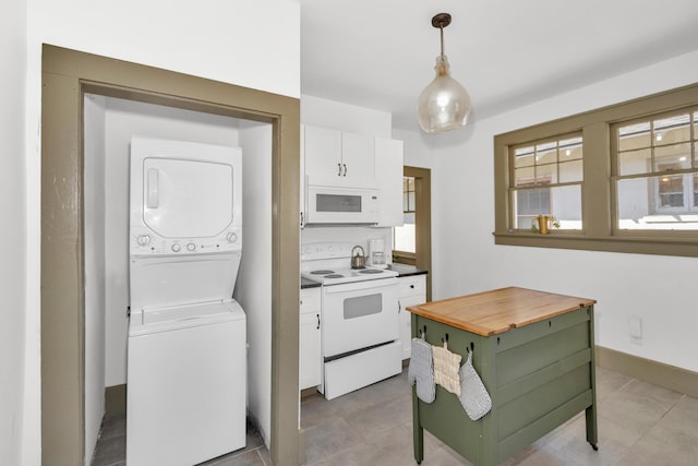 kitchen with stacked washer and dryer, white cabinetry, hanging light fixtures, light tile patterned floors, and white appliances