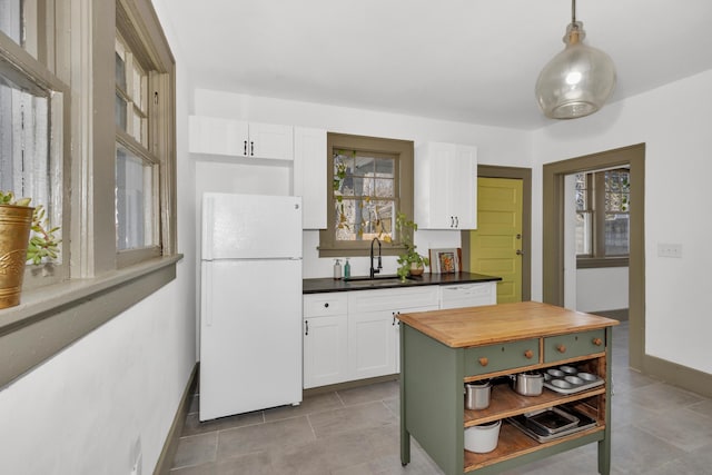 kitchen with sink, white cabinetry, a center island, decorative light fixtures, and white fridge