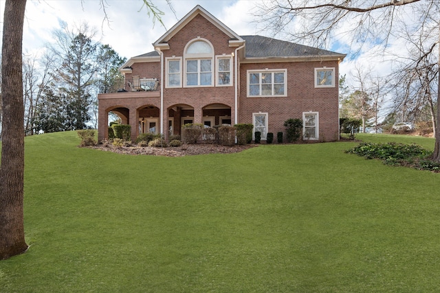 back of house with a lawn, a balcony, and brick siding