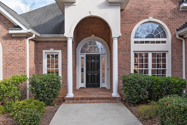 entrance to property with brick siding and roof with shingles