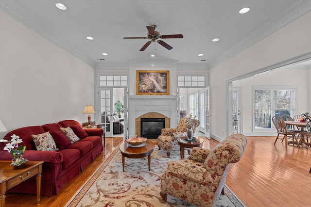 living area featuring a glass covered fireplace, recessed lighting, light wood-type flooring, and ornamental molding