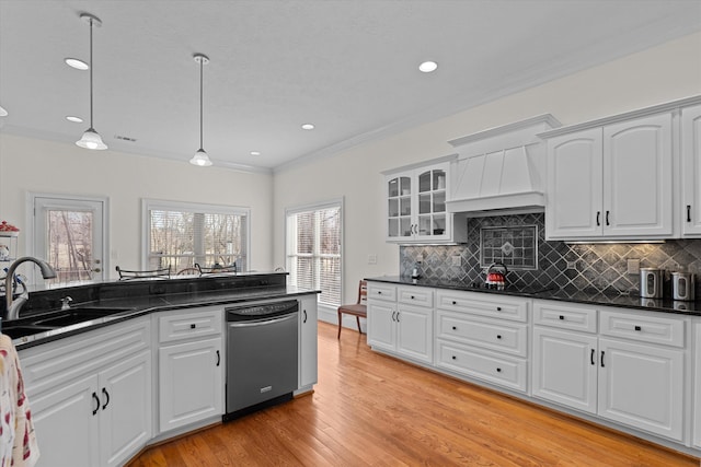kitchen featuring light wood-style flooring, a sink, stainless steel dishwasher, dark countertops, and crown molding