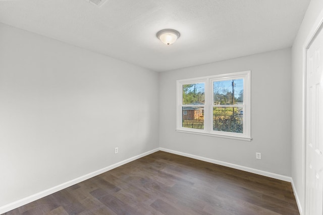 unfurnished room featuring baseboards and dark wood-style flooring